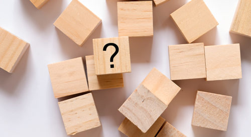 top-down view of blank wooden block on a white background. the block in the center has a question mark on it.