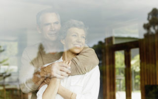 Thoughtful mature couple looking out through window at home