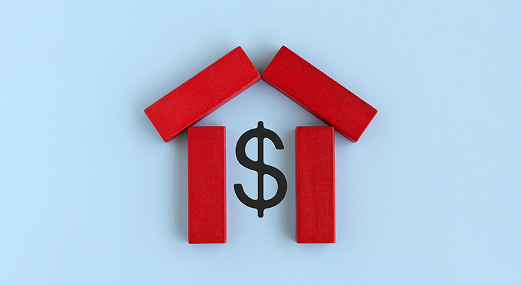 wooden blocks laid on a flat background. The block are arranged in a basic house shape, and are surrounding a dollar sign in the middle.