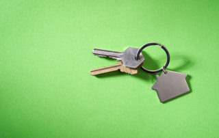 House keys with house shaped keychain, isolated on green background